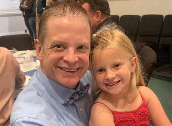 Dr. Michael J. Smith poses with his daughter Harper at a formal gathering.